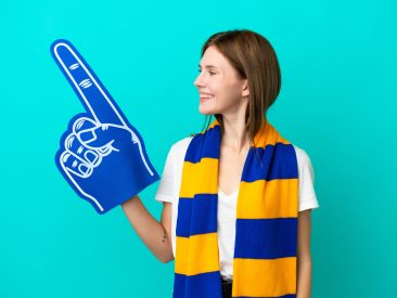 Young sports fan woman isolated on blue background looking side