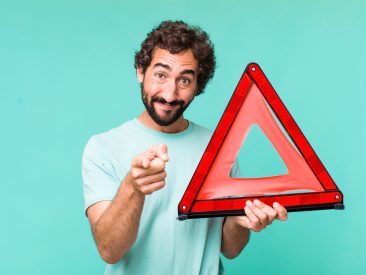 young adult hispanic crazy man with a car emergency triangle